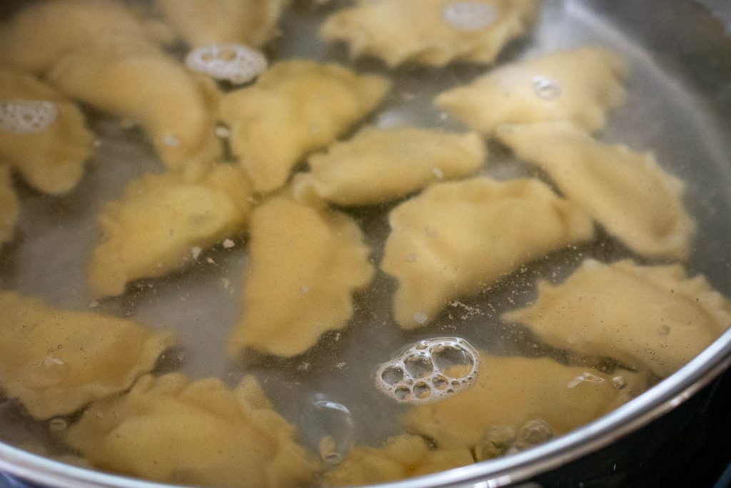 Curd cheese filled dumplings boiling in a pan.