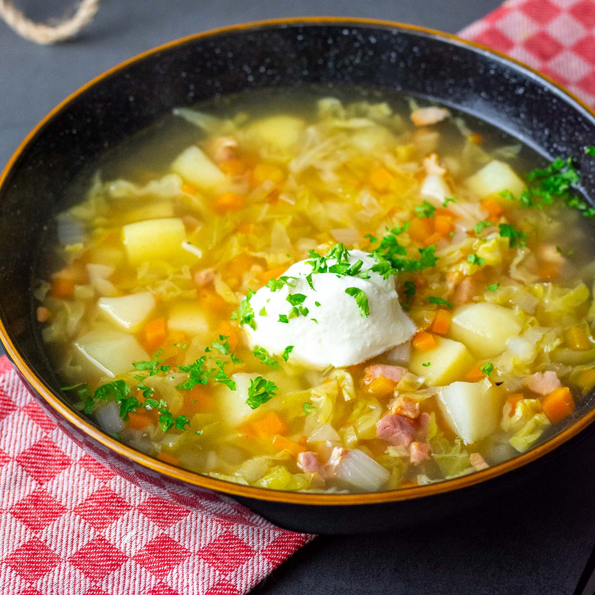 Lithuanian Cabbage soup with bacon served with a dollop of sour cream.
