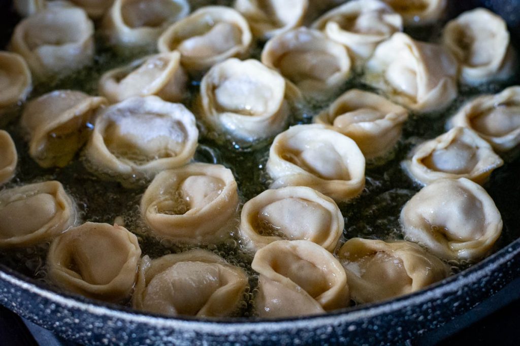 Pork dumplings in a frying pan with oil. 