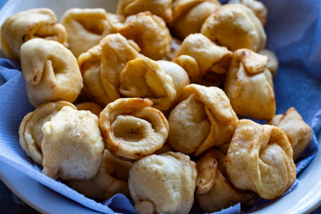 Golden brown fried pork dumplings in a bowl lined with paper towels. 