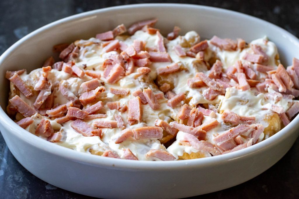 Bits of ham on top of the sour cream smeared dumplings. 
