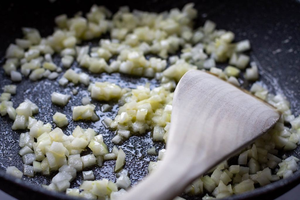 Finely chopped onions sauteeing in a frying pan.