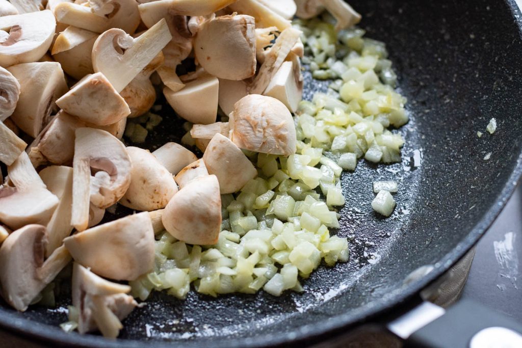 Quartered mushrooms added to the onion pan.