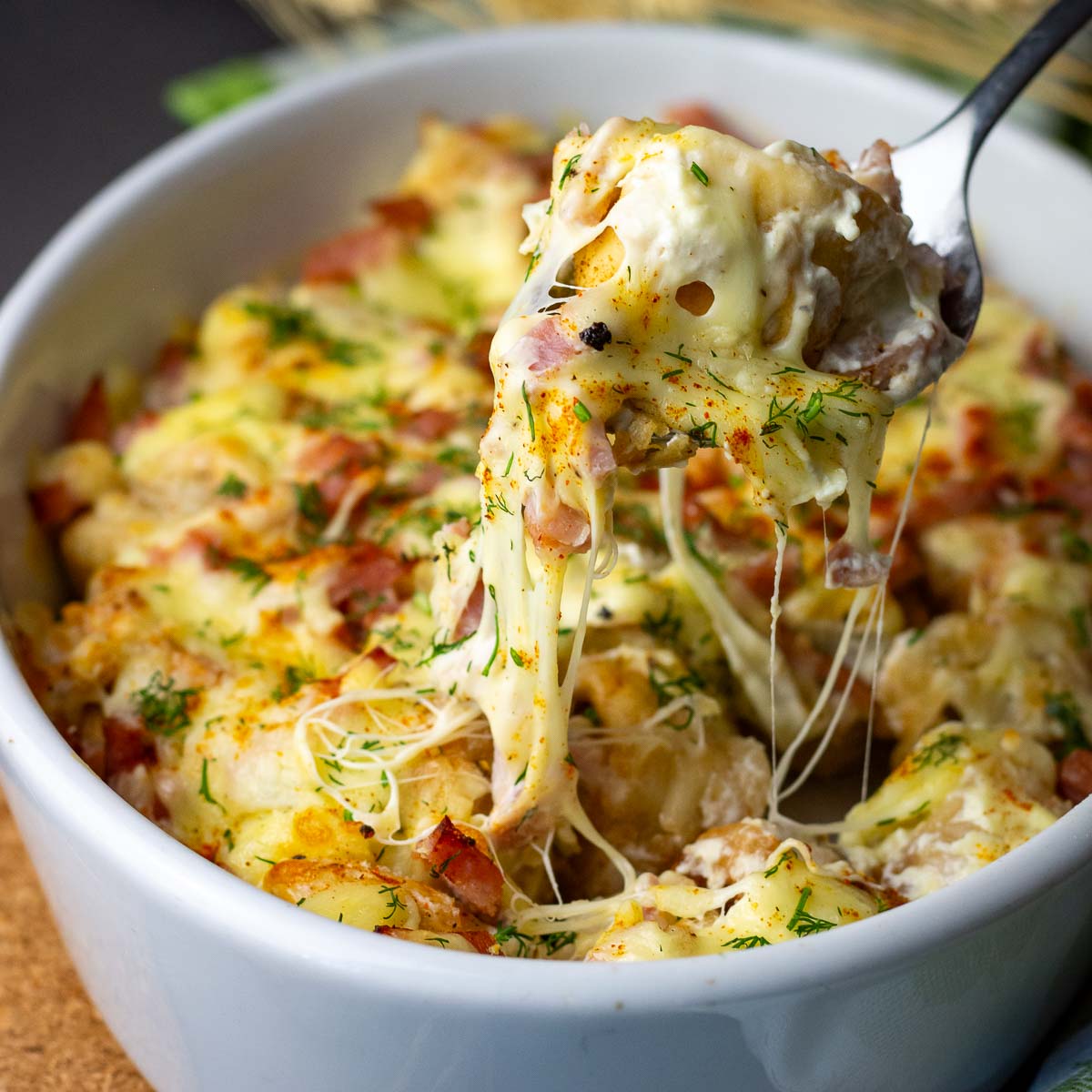 Cheesy Lithuanian Pork Dumplings casserole with a spoonful being taken out with cheese strings pulling. 