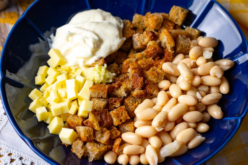 Fried bread, beans, cheese, garlic and mayo in a bowl. 