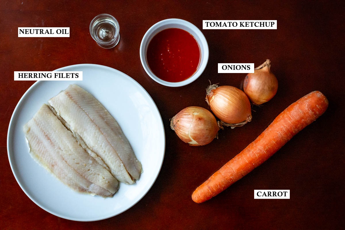 Ingredeints for Lithuanian Herring With Sauteed Onions and Carrots on a wooden table.