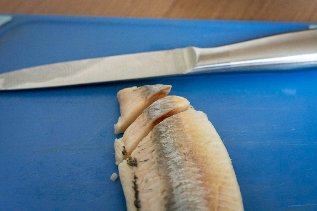 Slicing herring into strips.
