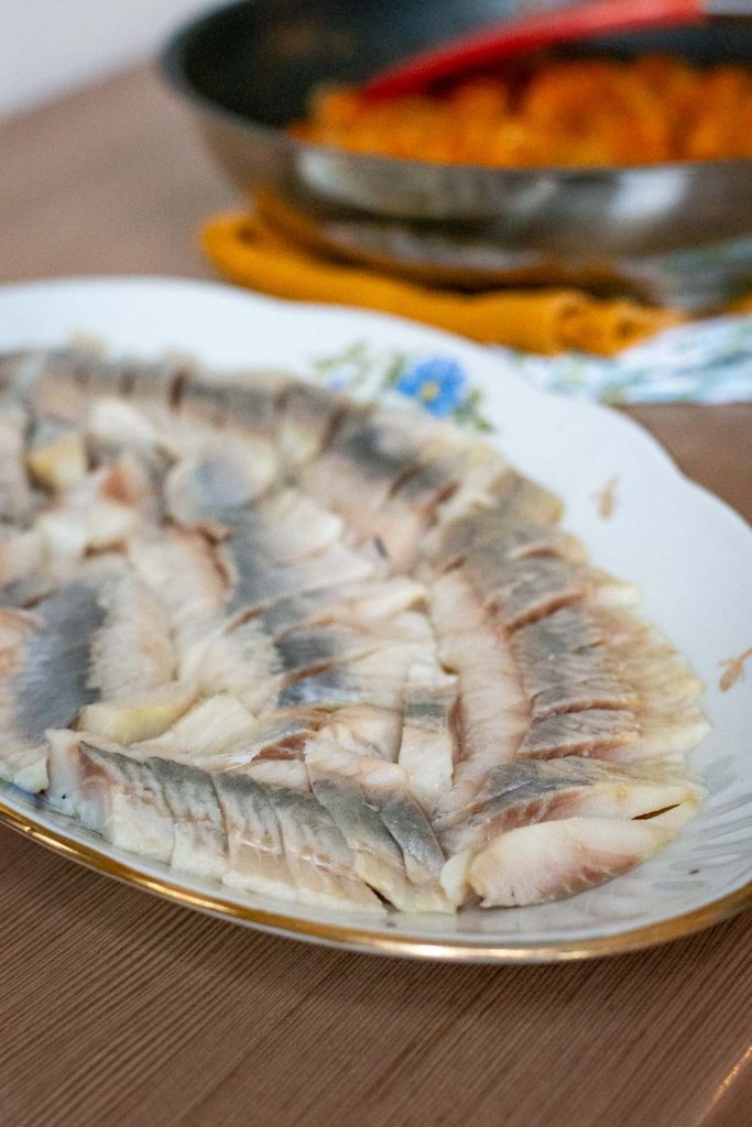 Sliced herring arranged in an oblong dish.