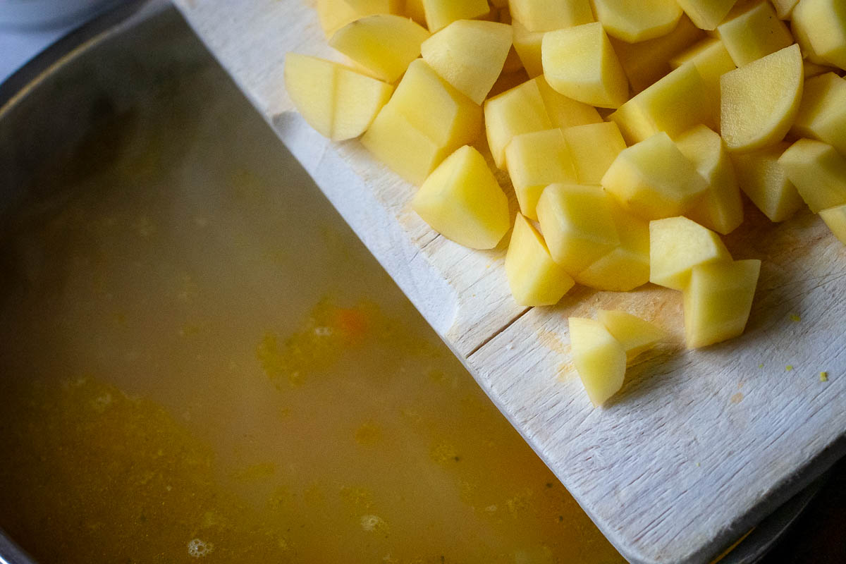 Adding cubed potatoes to the bean soup. 