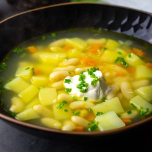 Lithuanian White Bean Soup With Potatoes in a black bowl.