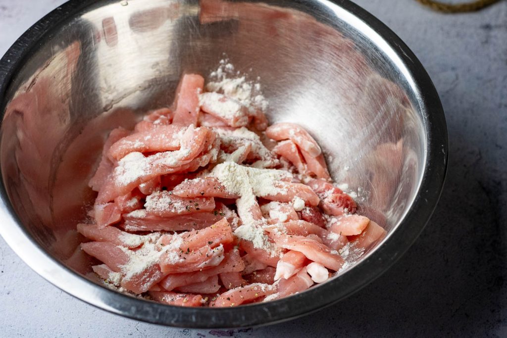 Pork strips being mixed with flour.