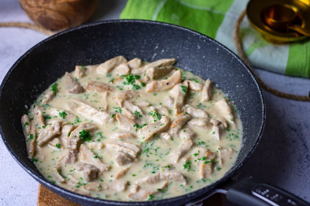 Lithuanian pork in sour cream sauce in a large frying pan.