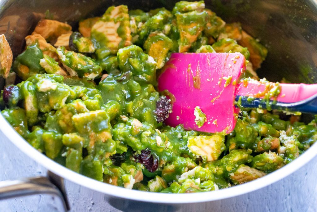 Mixing the cookie into the green condensed milk mixture with a pink rubber spatula.