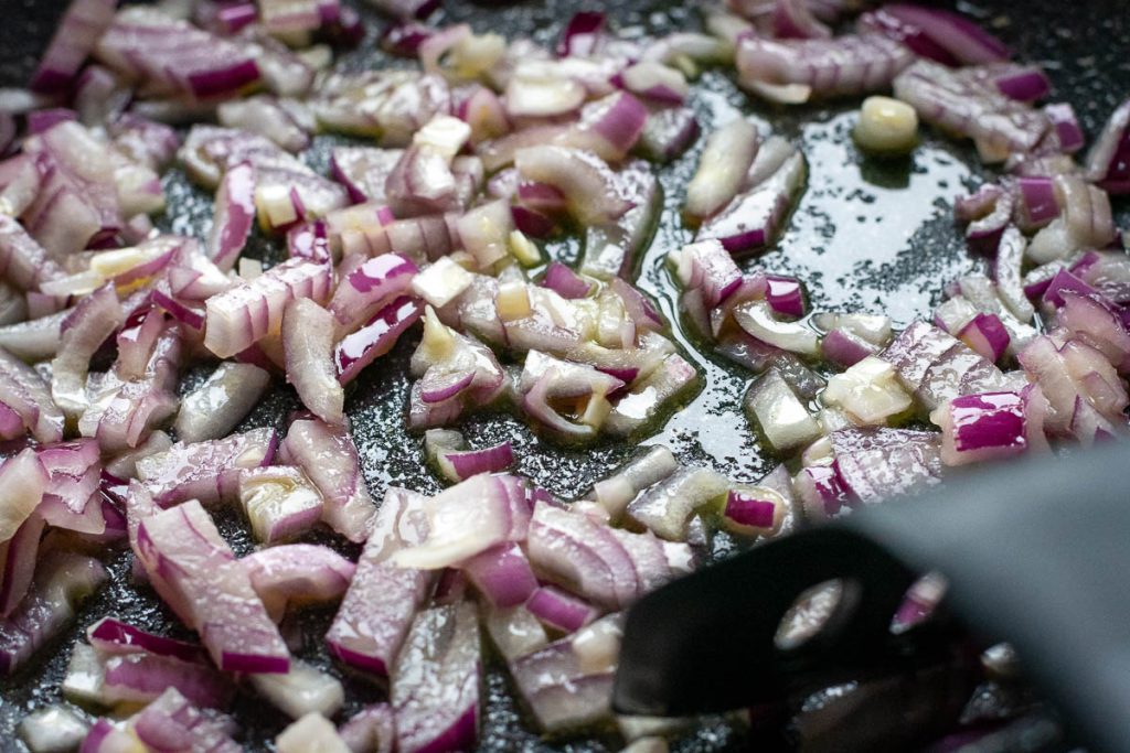 Chopped red onion being sauteed in the pan.
