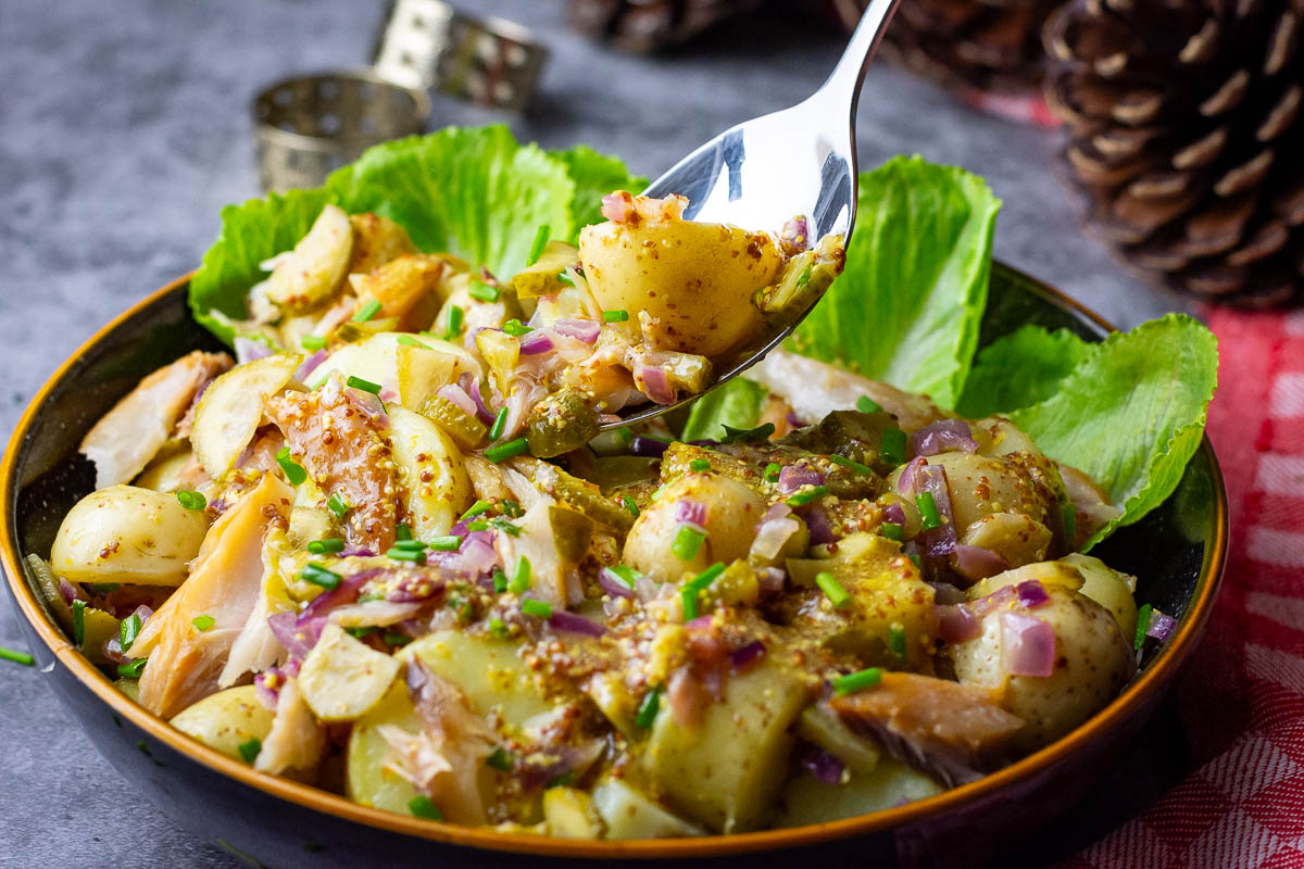 A spoonful of Lithuanian Smoked Mackerel and Potato Salad being taken out of a bowlful.