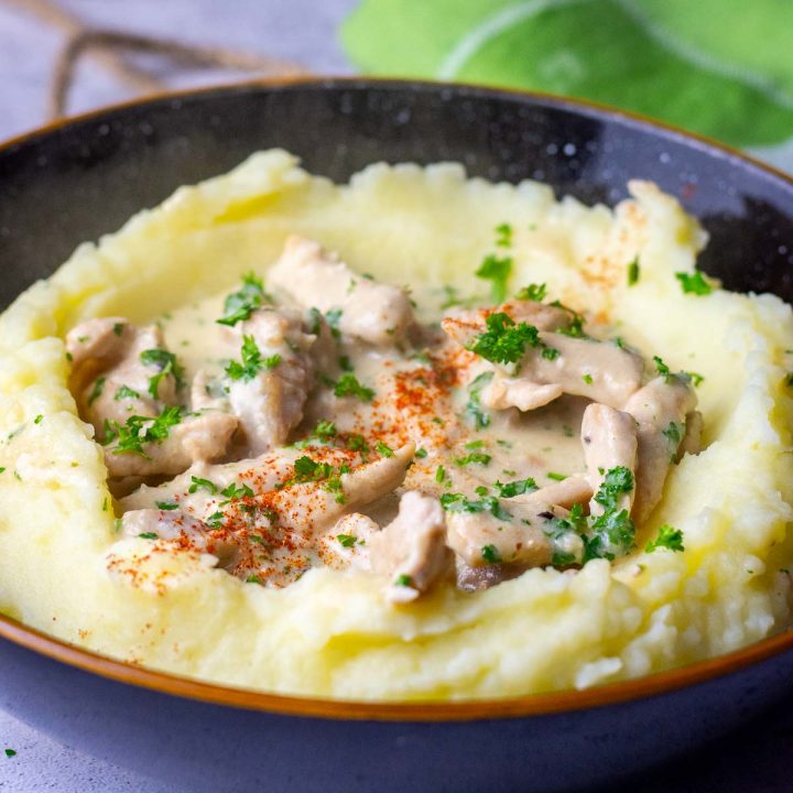 Creamy Lithuanian pork in sour cream sauce on a bed of mashed potatoes.