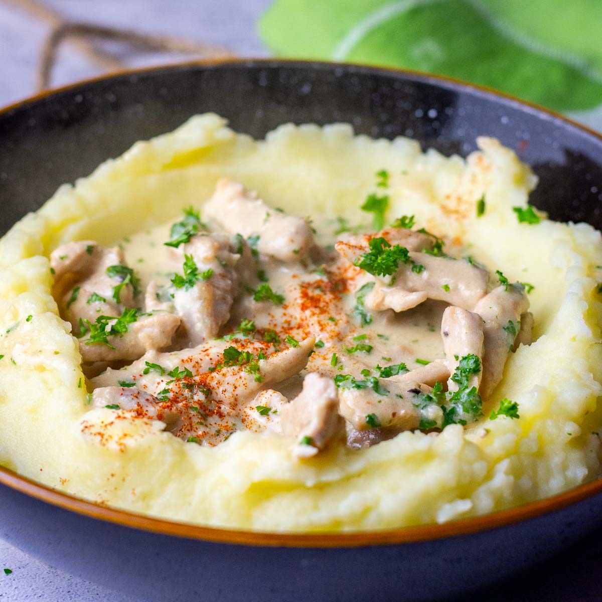 Creamy Lithuanian pork in sour cream sauce on a bed of mashed potatoes.