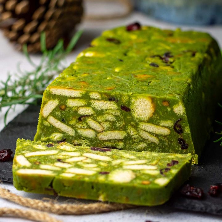 A slice of no bake matcha cake cut from a whole loaf of Lithuanian lazy cake.