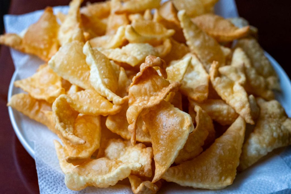 Flipping pastry pieces in hot oil with two forks.