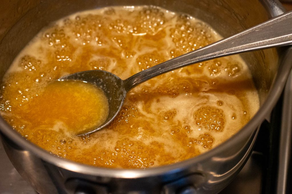 Honey glaze for Lithuanian anthill gently bubbling in a saucepan.