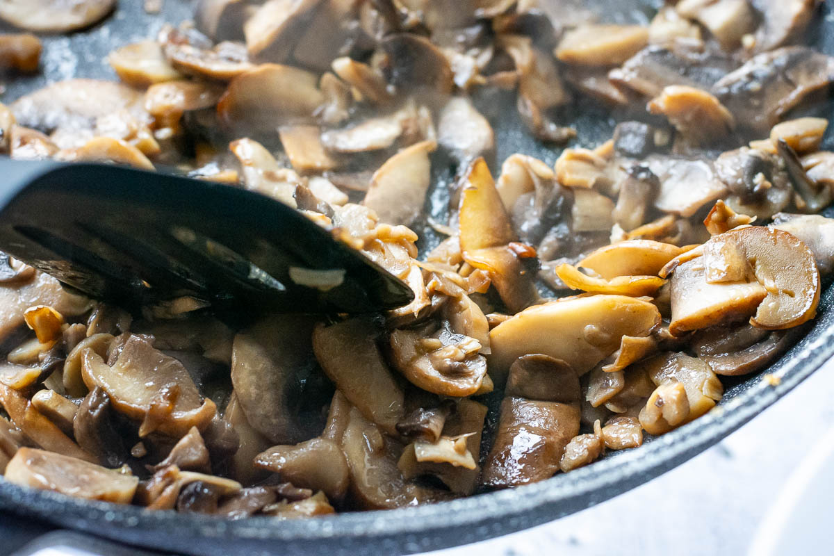Mushrooms cooking in a large frying pan. 