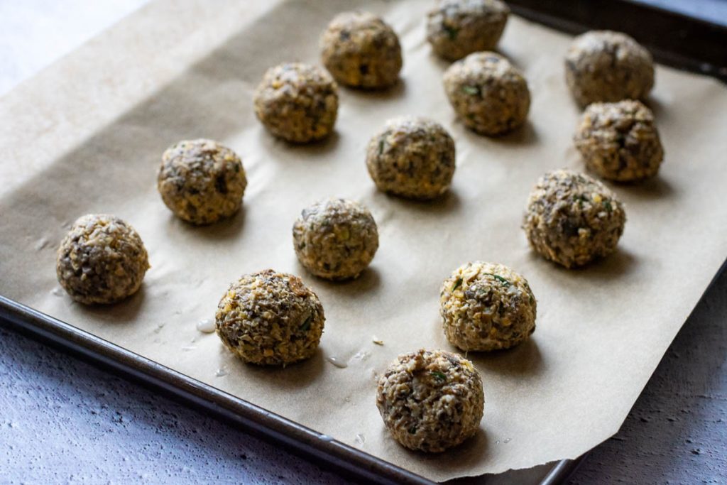 Mushroom balls arranged on a baking sheet. 