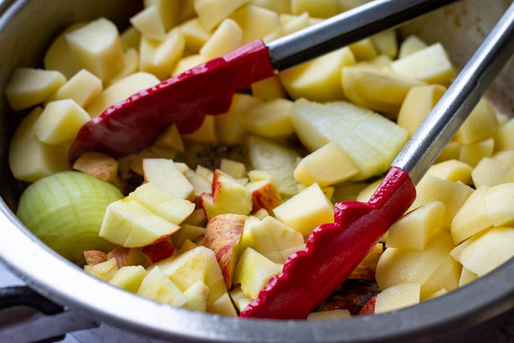 Onions, apples, and potatoes added to the sausage pan.