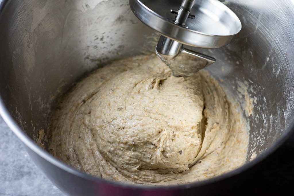 Rye dough wrapping around dough hook attchment in a stand mixer.