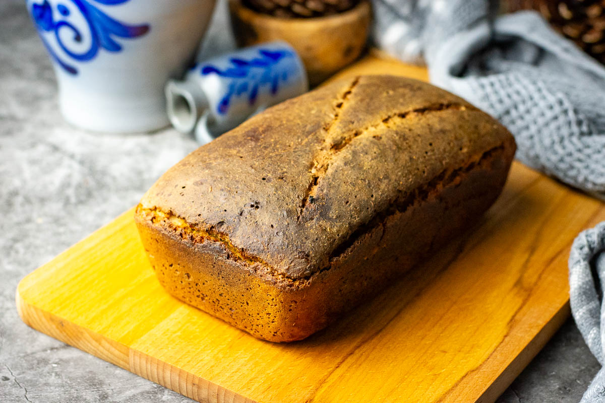 A loaf of rye sourdough bread on a wooden cutting board.