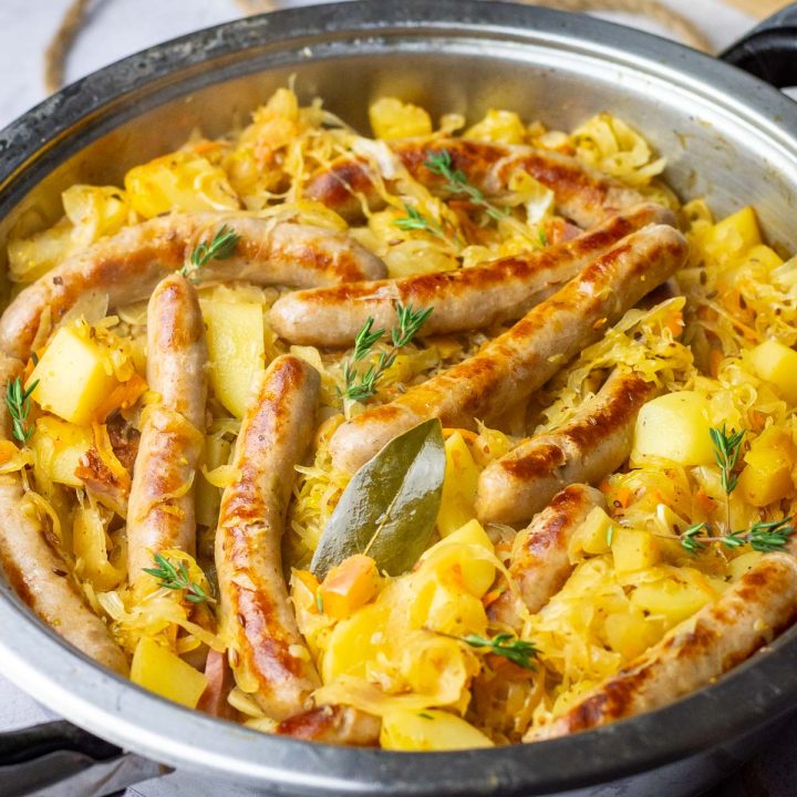 Lithuanian sauerkraut with sausages and potatoes in a large pan.