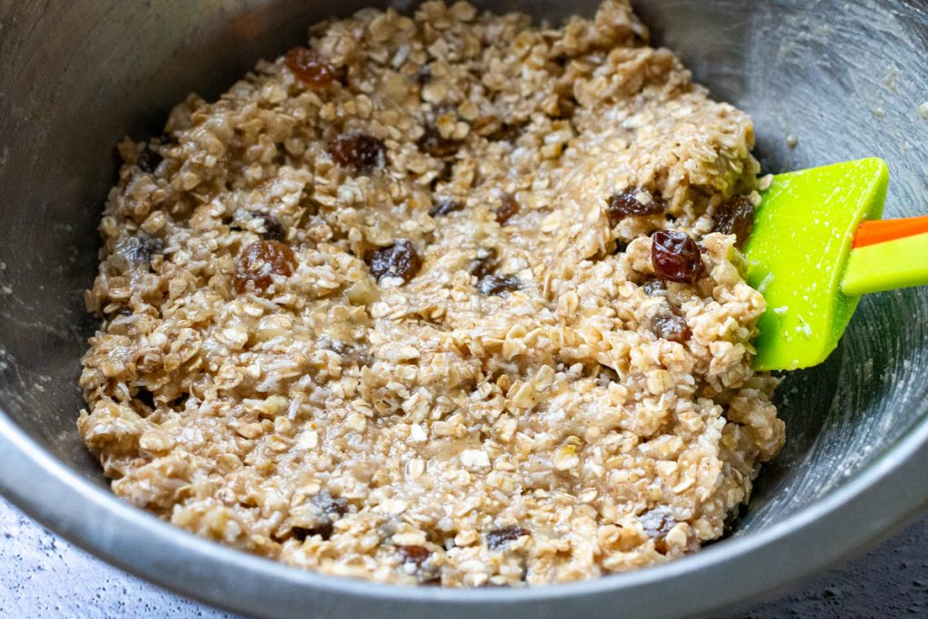 Mixed oatmeal and banana cookie dough in a large metal bowl. 