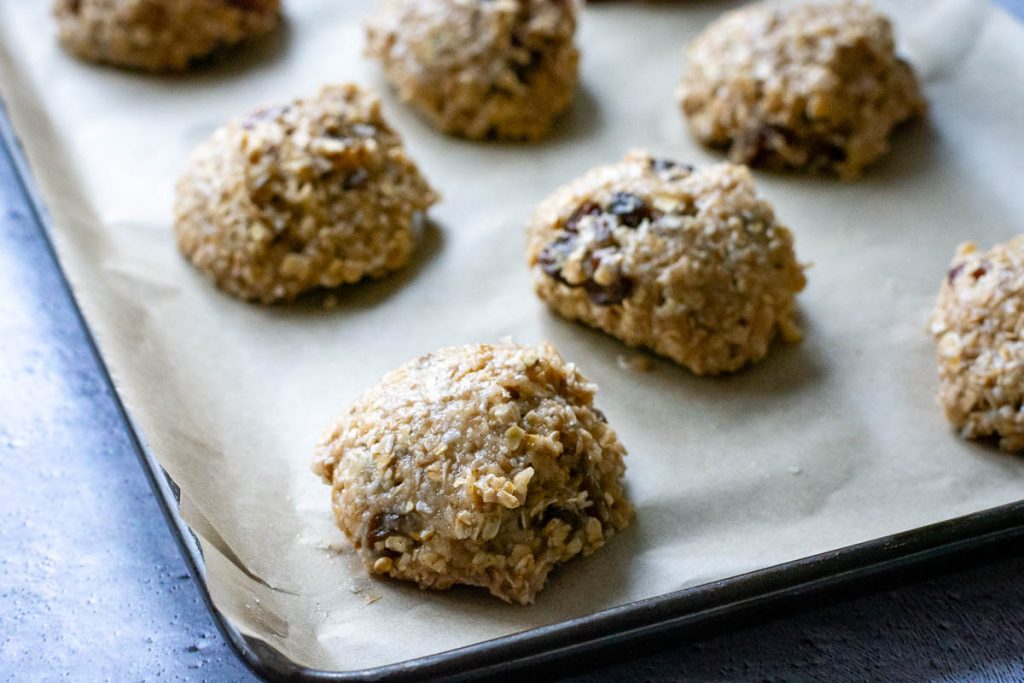 Cookie dough divided into mounds and placed on a parchment paper liked baking sheet. 