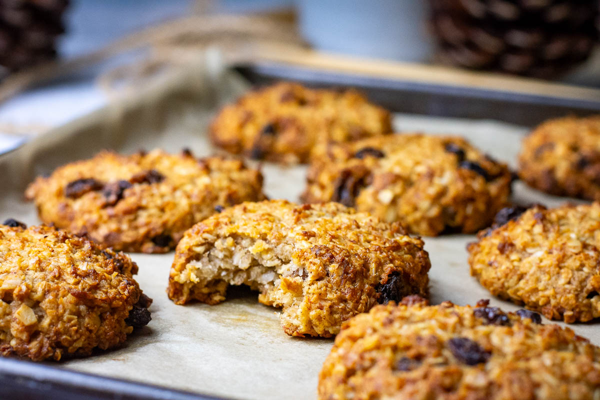 A bitten into Lenten Cookie amongs other oat cookies on a baking sheet. 
