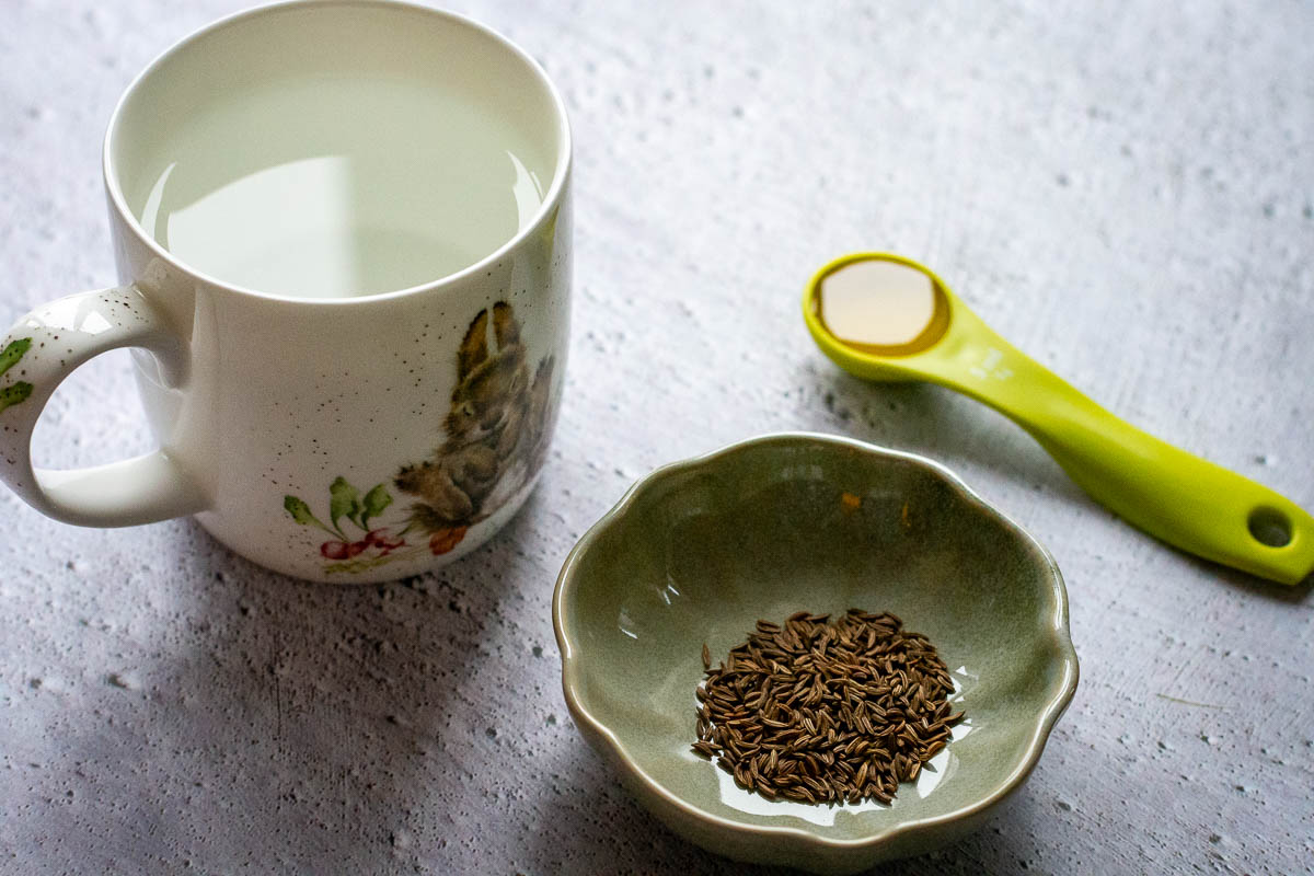 Ingredients for Lithuanian caraway seed tea recipe on a grey surface. 