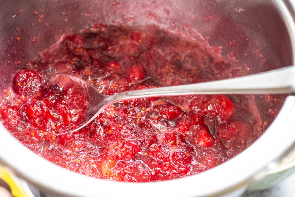 Cranberries and sugar cooking in a pan.