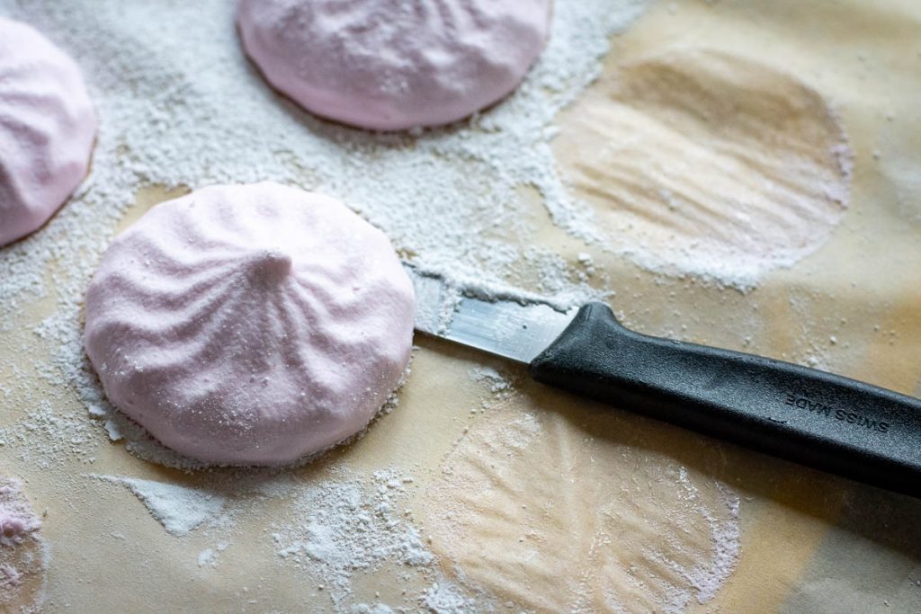 Running a thin bladed knife under the marshmallows to release them from parchment paper.