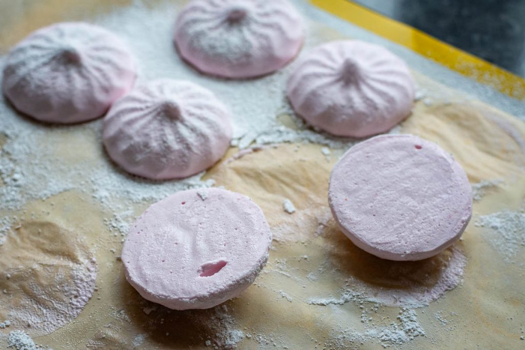 Cranberry marshmallow halves on a parchment paper lined cookie sheet.