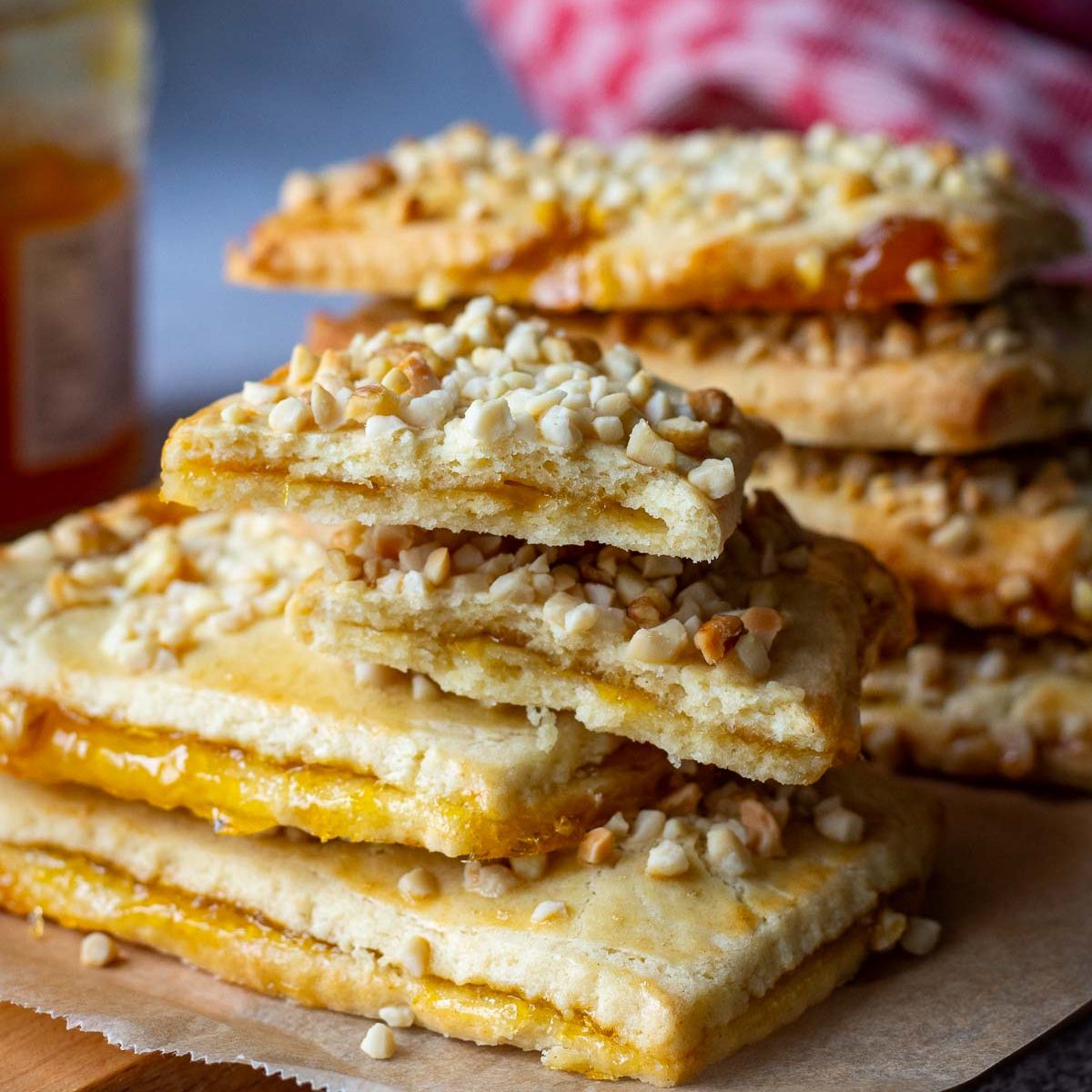 A stack of Lithuanian Jam-Filled Sugar Cookies with nut topping on a wooden board.
