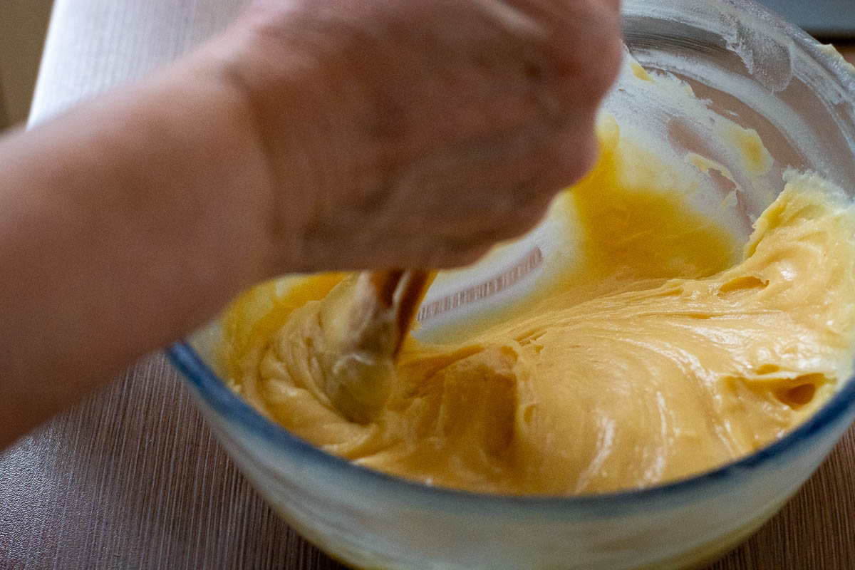 Mixing the eggs into the dough in a glass bowl.