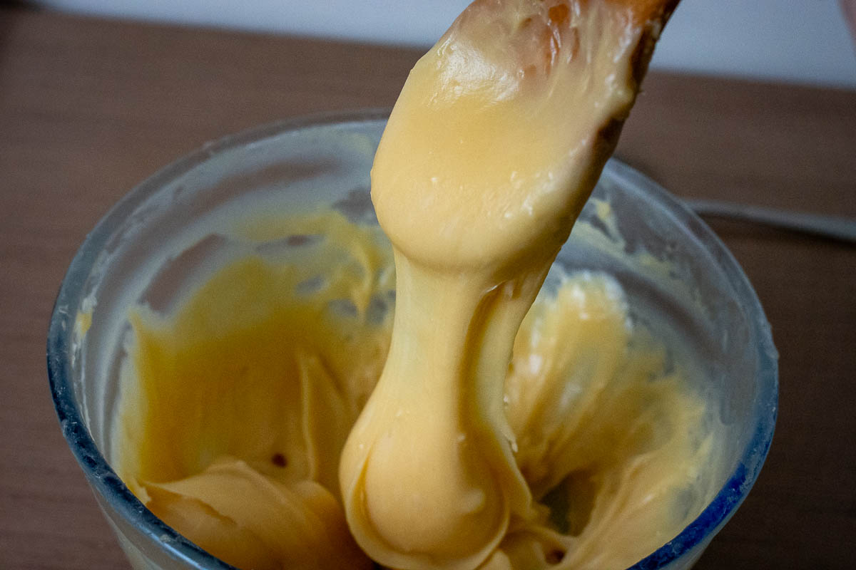 Choux pastry dough slowly falling off the wooden spoon.