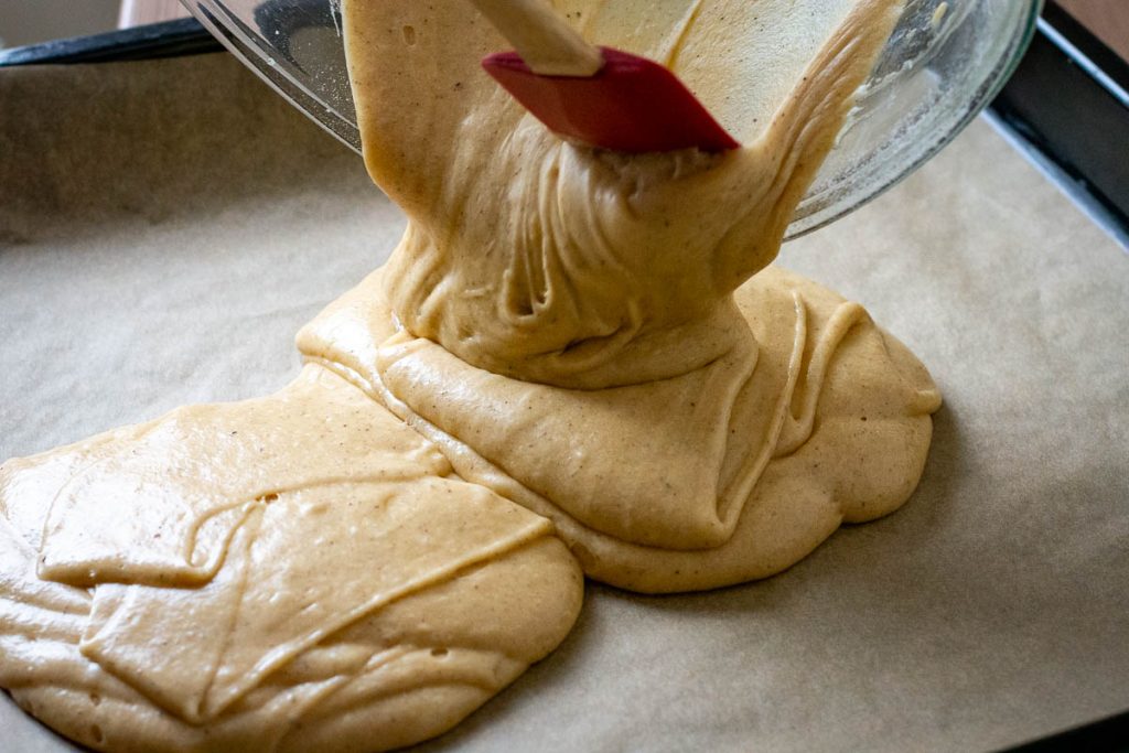 Pouring the Lithuanian honey cake batter onto a parchment lined baking sheet.