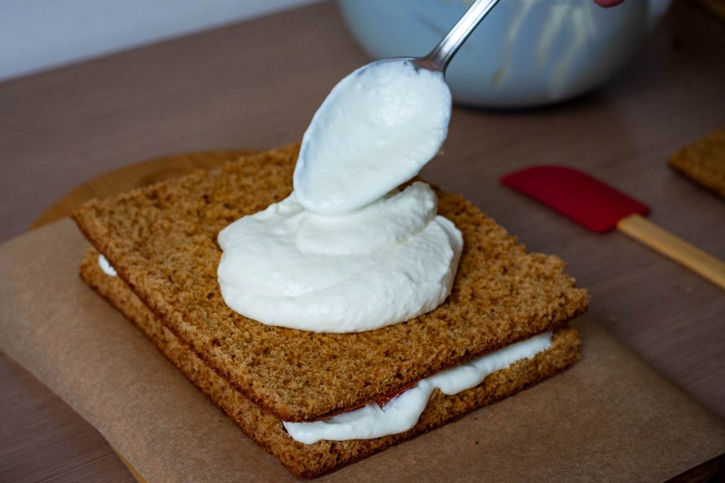 Assembling Lithuanian Honey Cake Sodzius by layering sponge, sour cream filling and jelly cubes.