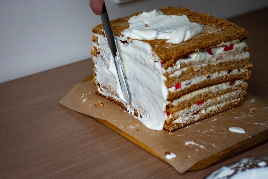 Covering Lithuanian honey cake in friosting.
