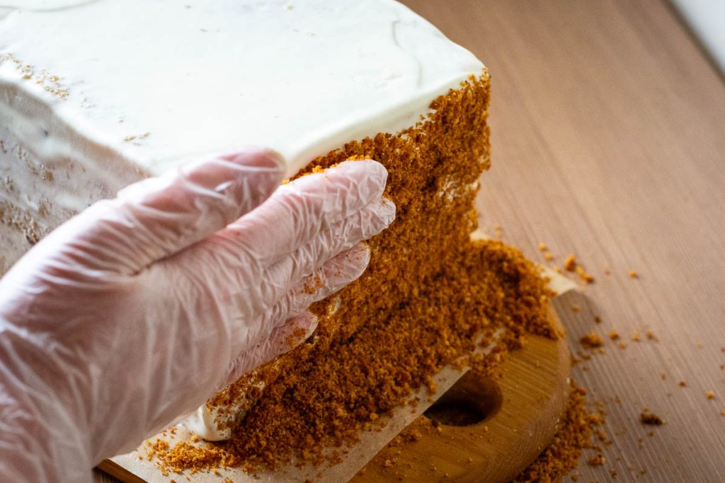 Covering the Lithuanian Honey Sponge cake in crumbs.