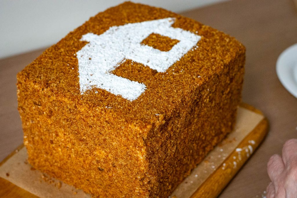 Decorated Sodzius cake with a house made from powdered sugar on top.
