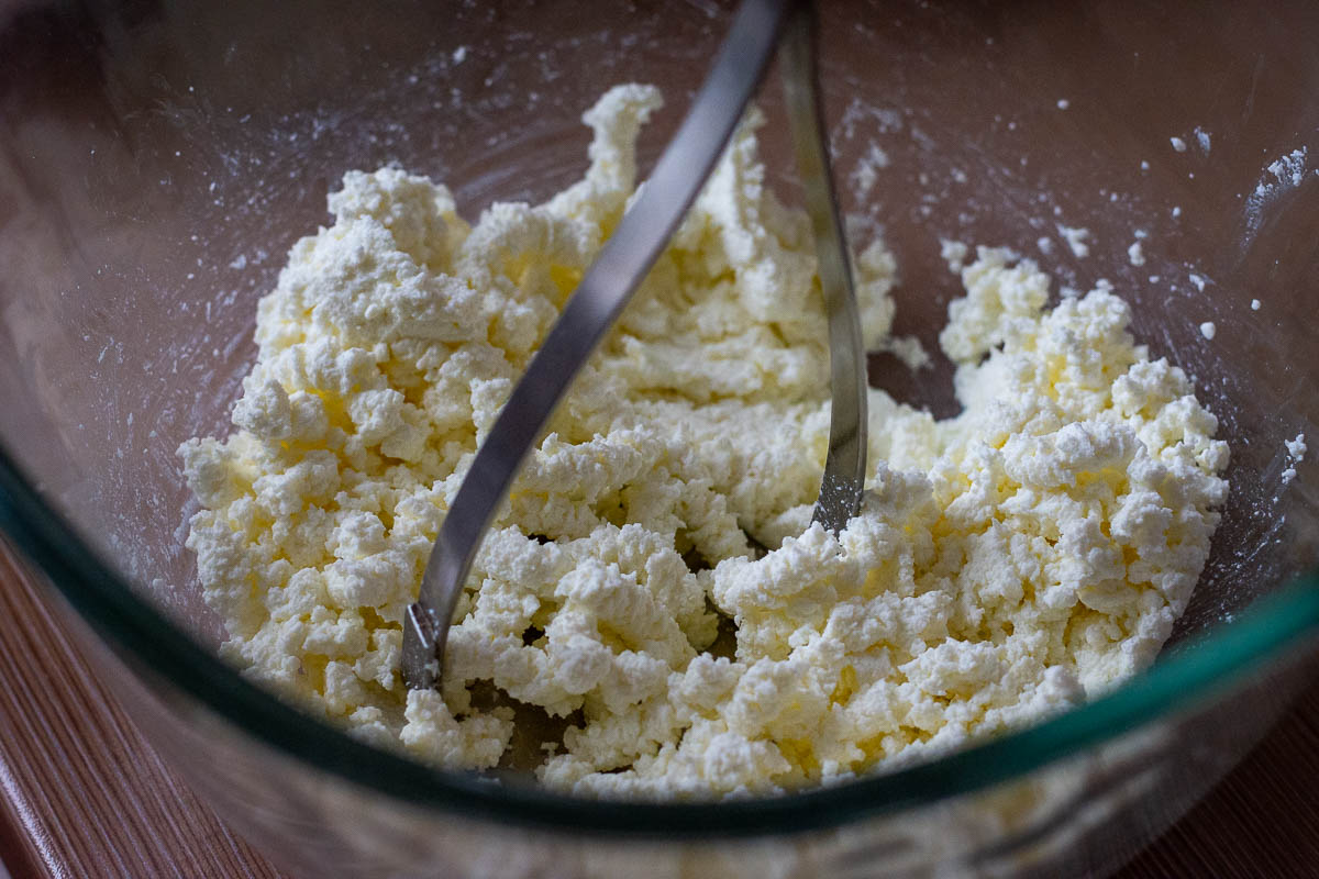 Mashing farmer's cheese with a potato masher.