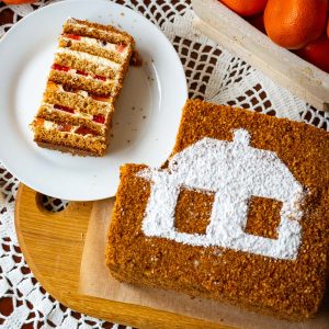 A slice of Lithuanian Honey Sponge cake next to the whole Lithuanian Cake "Sodzius".
