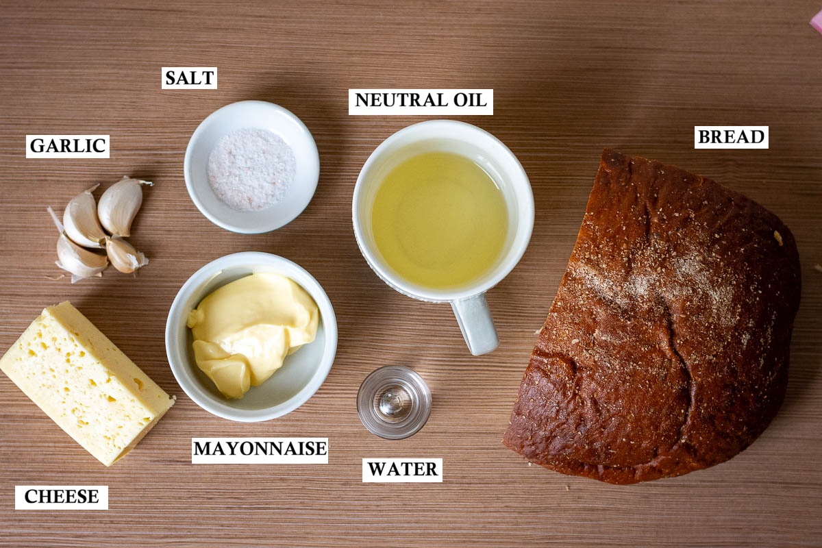 Labeled ingredients for Lithuanian fried bread with cheese sauce on a wooden surface. 