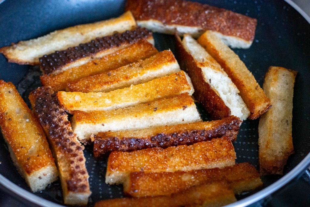 Deep golden brown Lithuanian fried bread in a frying pan. 