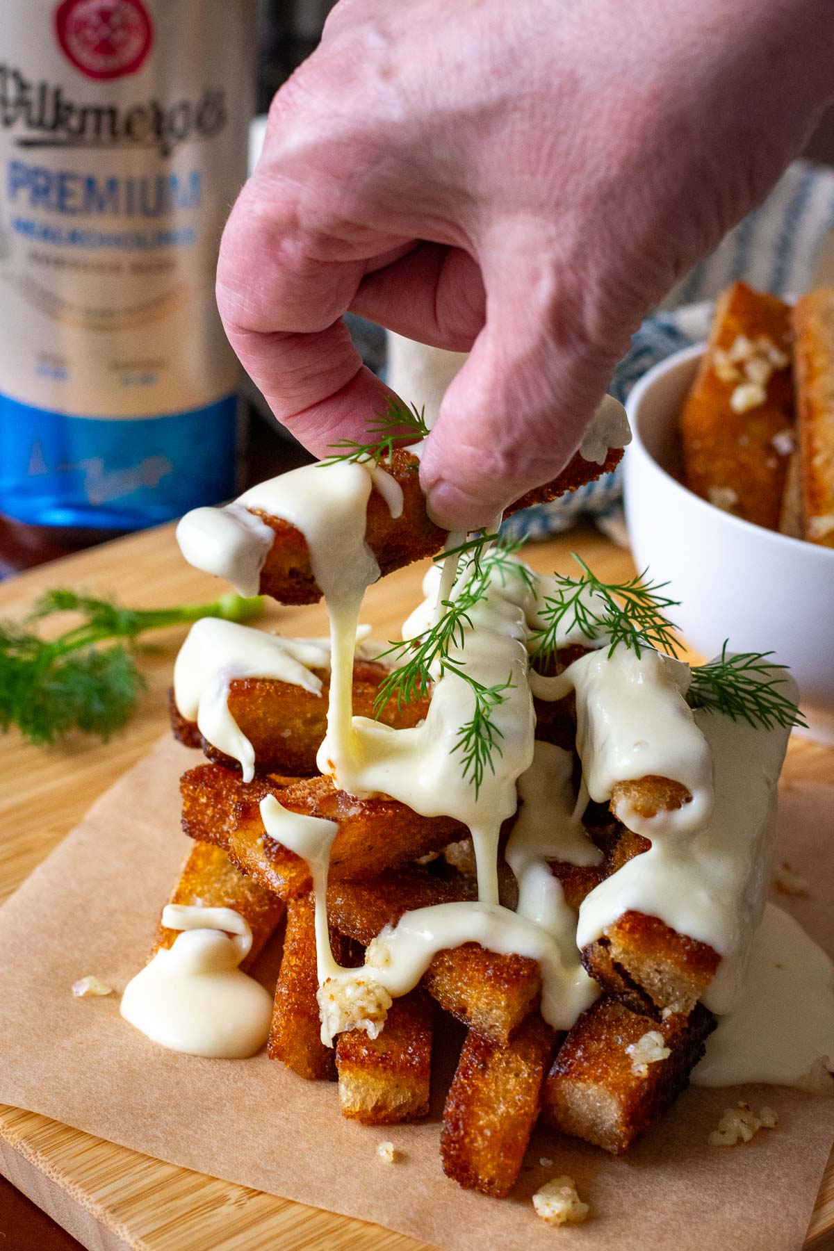 Lithuanian Fried garlic bread with cheese being garnished with dill.